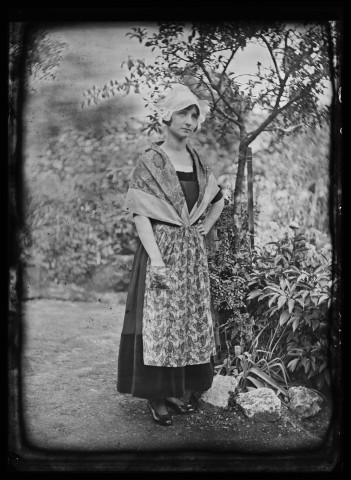 Jeune femme en costume traditionnel, vue en pied, dans un jardin