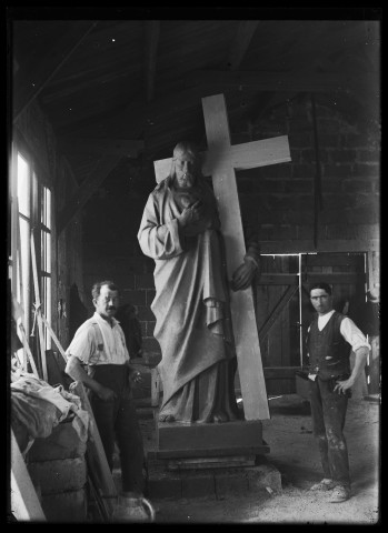 Deux praticiens de Louis Hertig posant dans un atelier autour du Christ portant la Croix du monument aux morts de Trévillers