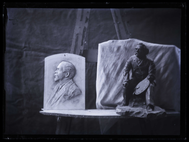Deux sculptures dans l'atelier : un portrait d'homme de profil en bas-relief et un groupe sculpté représentant un peintre