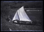 James Hertig et un autre jeune homme dans un voilier du SNB sur le Doubs, Mme Hertig assise à côté sur un talus