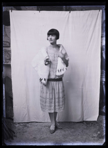 Jeune femme à la coupe garçonne, vue en pied, avec un châle de fourrure sur les épaules