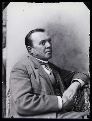 Portrait d'un homme posant de 3/4 droit dans un fauteuil en osier