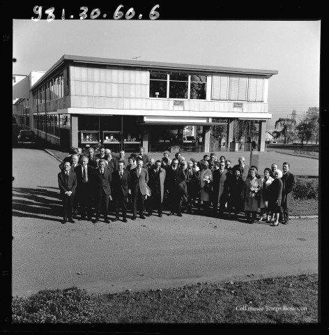 39MDT412 - Photographie de groupe du personnel prise devant l'entrée administrative de l'usine de Palente : négatif (noir et blanc).