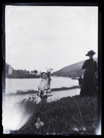 James Hertig enfant, en promenade au bord du Doubs, brandissant un bouquet de fleurs sauvages ; Louise à l'arrière-plan