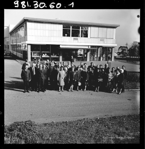 39MDT412 - Photographie de groupe du personnel prise devant l'entrée administrative de l'usine de Palente : négatif (noir et blanc).