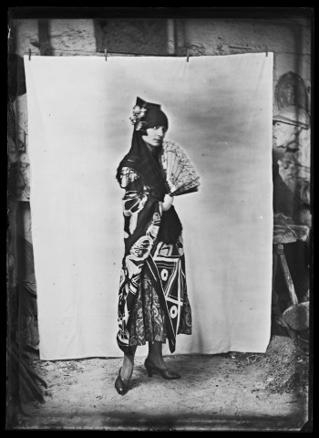 Jeune femme vue en pied, en robe imprimée, posant en Espagnole, avec mantille et éventail